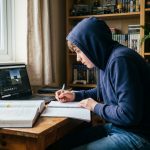Adolescent étudiant le game design tout en révisant les mathématiques sur son bureau à la maison