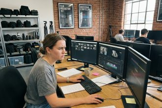 Jeune femme concentrée travaillant sur montage vidéo en studio